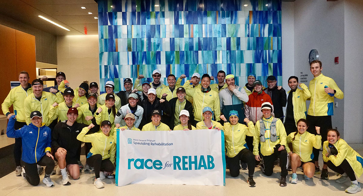 Contestants in yellow jackets posing with a Race for Rehab banner.