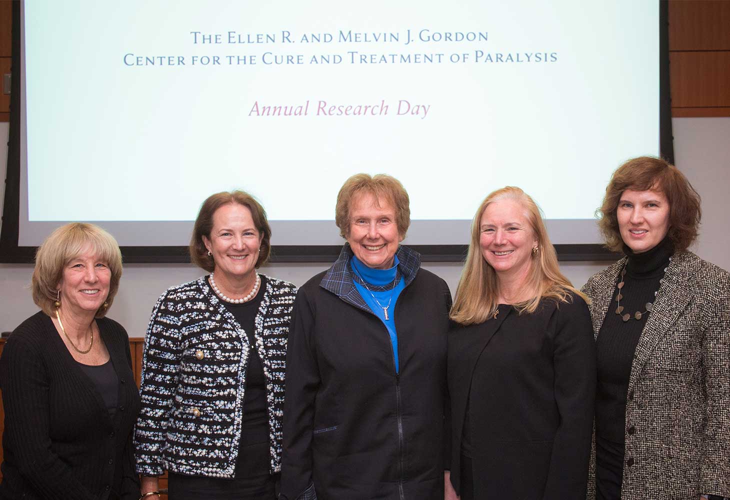 Five women, including Ellen Gordon, pose in front of a sign for the Gordon Center Research Day.