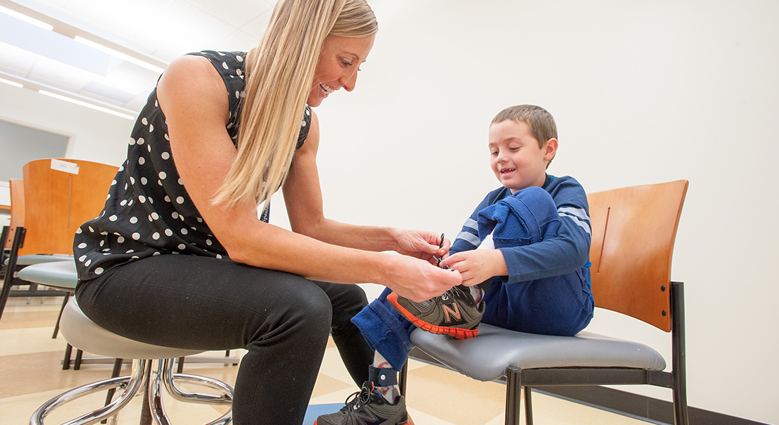physical therapist helping pediatric patient with shoes