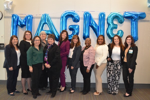 Group photo celebrating magnet status behind balloons that spell magnet