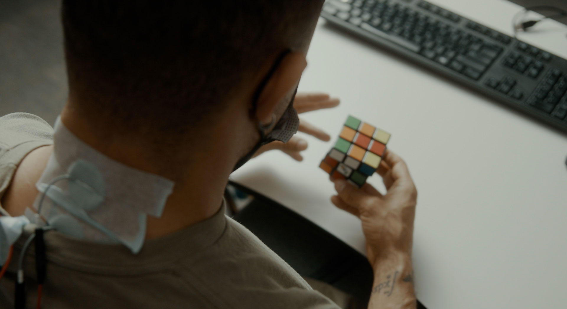 A man with electrodes taped over his spine does a Rubiks Cube.