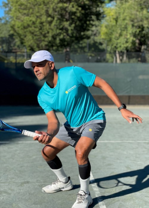 Amit, a fit man in his 30's, swinging a racket on a tennis court.