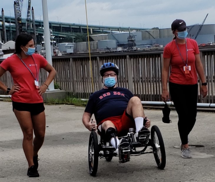 John at a race in his wheelchair, flanked by two volunteers.