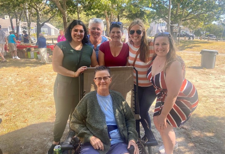 Patty, an older woman, in a lounge chair at the park, surrounded by five other smiling women.