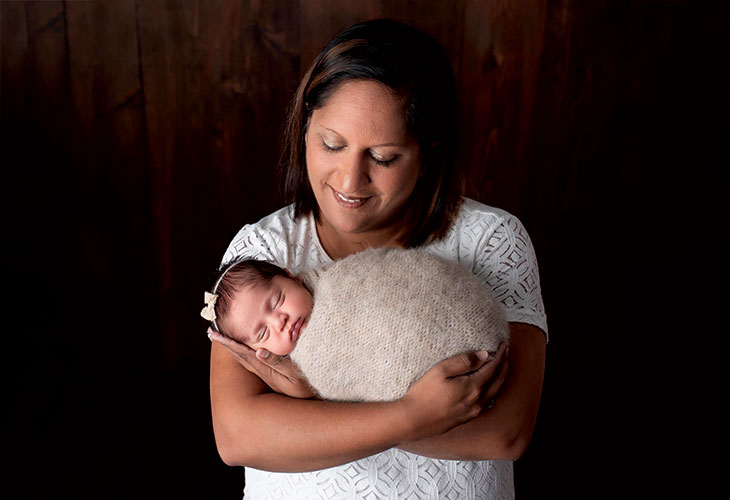 Priya cradles her swaddled baby.