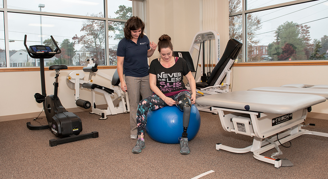 Patient with prosthetic leg rehabbing with exercise ball at Spaulding Outpatient Center Plymouth