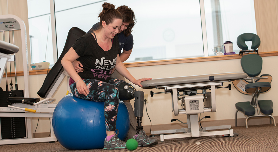 Patient with prosthetic leg rehabbing with exercise ball at Spaulding Outpatient Center Plymouth
