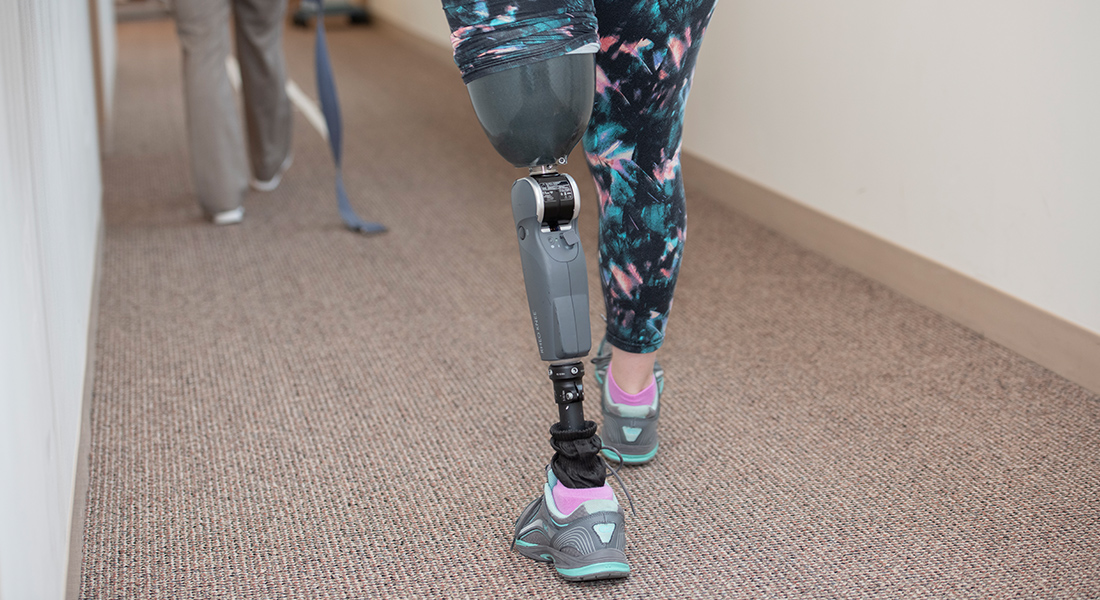 Patient with prosthetic leg walking through hall at Spaulding Outpatient Center Plymouth